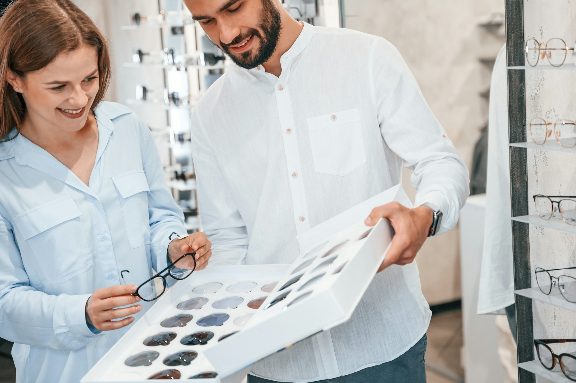 Standing and smiling. Man and woman in the glasses store. Helping to choose product